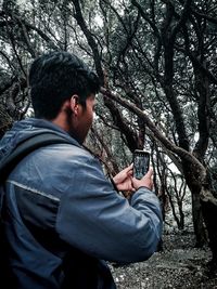 Young man using mobile phone in forest