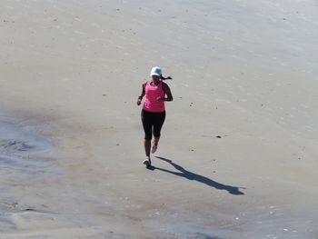 High angle view of woman jogging on sand at beach