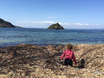 Rear view of boy on beach against sky