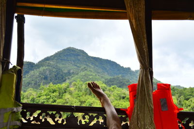 Low section of person on window against mountain