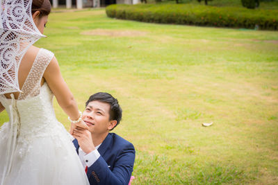 Groom proposing bride on field