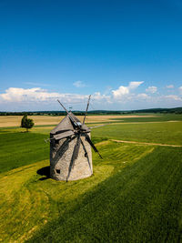 Traditional windmill on field against sky