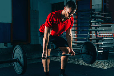 Male athlete exercising with barbell in gym