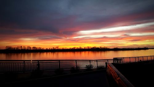 Scenic view of lake against cloudy sky at sunset