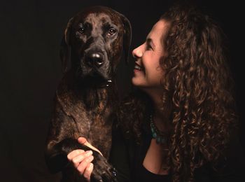 Portrait of woman with dog against black background