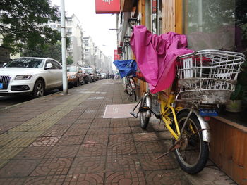 Bicycle on sidewalk by street against buildings in city