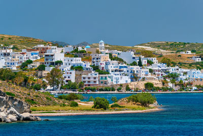 Buildings by sea against clear blue sky