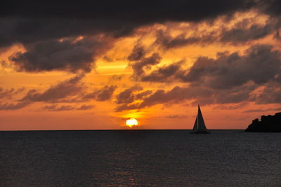 Boat sailing in sea against cloudy sky during sunset
