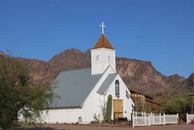 Low angle view of church against clear blue sky and mountains 