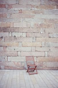 Empty bench against brick wall