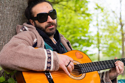 Close-up of man playing guitar by tree