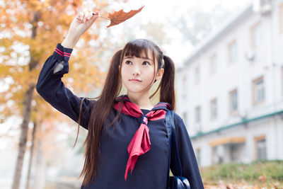 Beautiful young woman holding leaf standing outdoors