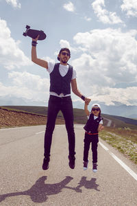 Father and son jump with black skateboard on the road against of mount everest in the summer