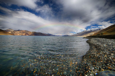 Scenic view of rainbow over sea against sky