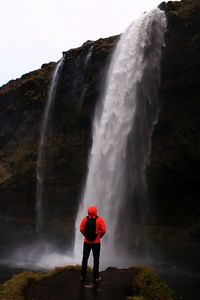 Man standing at the powerful seljalandsfoss waterfall 