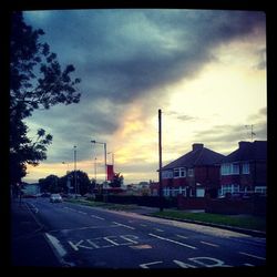 Cars on road against cloudy sky at sunset