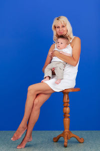 Low angle view of woman sitting against blue background