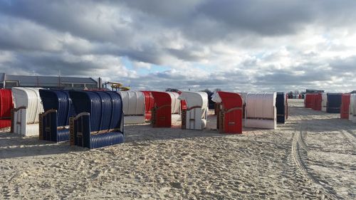 Row of hooded chairs on beach against sky