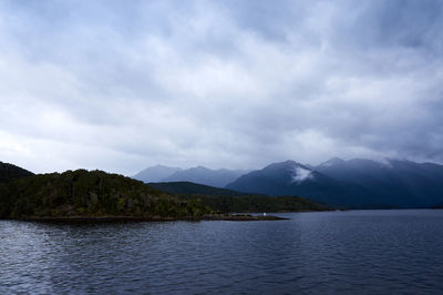 Scenic view of river and mountains against cloudy sky at dusk