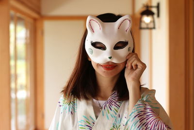 Portrait of smiling young woman wearing mask at home