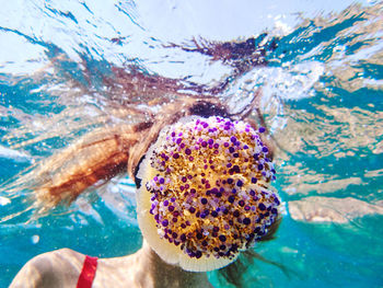 Unrecognizable young woman in diving mask swimming in deep transparent sea water and exploring jellyfish