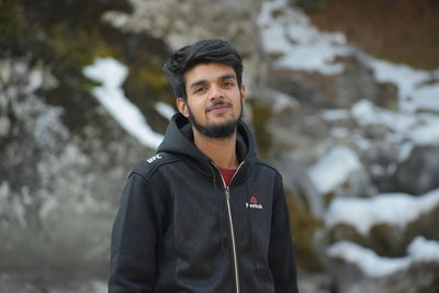 Portrait of teenage boy standing against mountain during winter