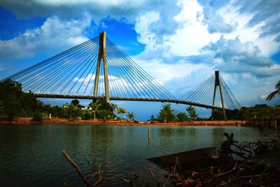 Suspension bridge over river against sky