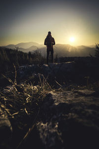 Silhouette man standing on field against sky during sunset
