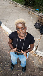 Portrait of young woman standing on footpath