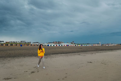 Rear view of woman walking on beach against sky