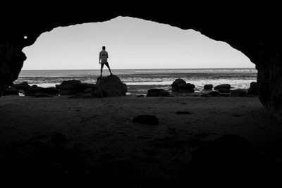 Silhouette people standing on rock by sea against sky