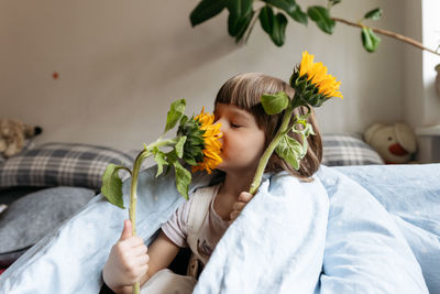 A toddler girl holding and smelling sunflowers