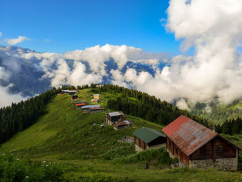 Scenic view of houses and trees on field against sky