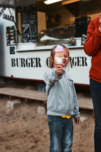 Little girl holding her ice cream in front of her face standing in front of food truck