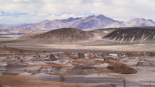 Scenic view of pumice stone field with andes mountains against sky.