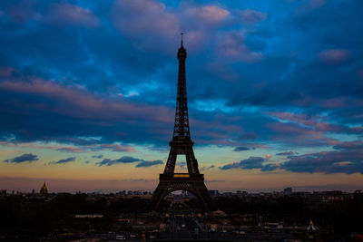 Communications tower in city against sky during sunset