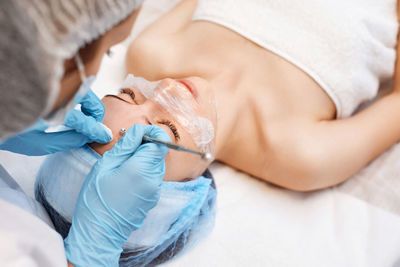 High angle view of doctor examining patient lying on bed at home