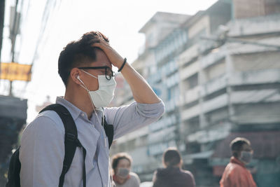 Man wearing protective mask while standing on street in city