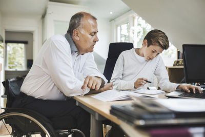 Disabled father assisting son in doing homework at home