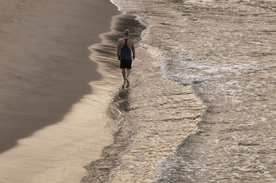 Rear view of man walking on beach