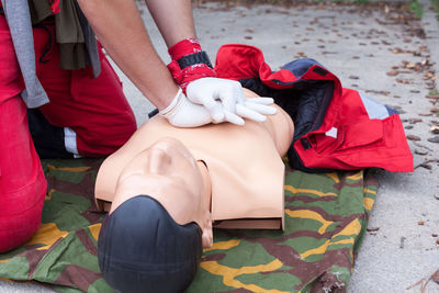 Midsection of paramedic performing cpr on mannequin