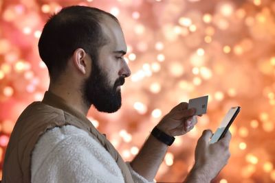 Side view of young man making mobile payment