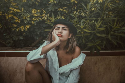 Portrait of young woman sitting by plants