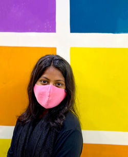 Portrait of young woman standing against yellow wall
