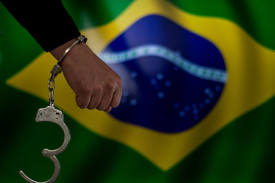 Cropped hand with handcuffs against brazilian flag