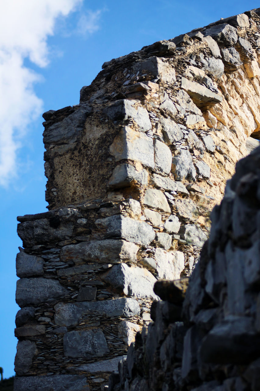 LOW ANGLE VIEW OF STONE WALL AGAINST ROCK