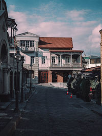 Footpath amidst buildings in city against sky