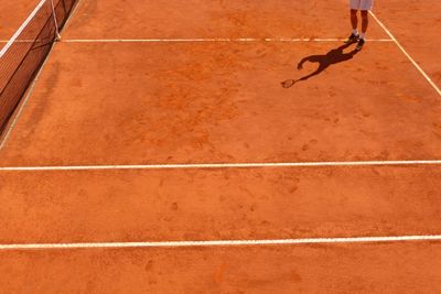 Low section of sportsman playing tennis on field