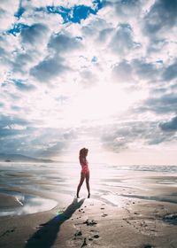 Woman standing at beach against sky