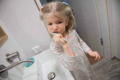 Girl brushing teeth in bathroom at home